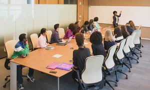 Woman leading a meeting of a group of people sitting around a table