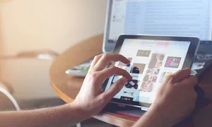 photo of someone using a tablet with the screen displaying a retail shopping website