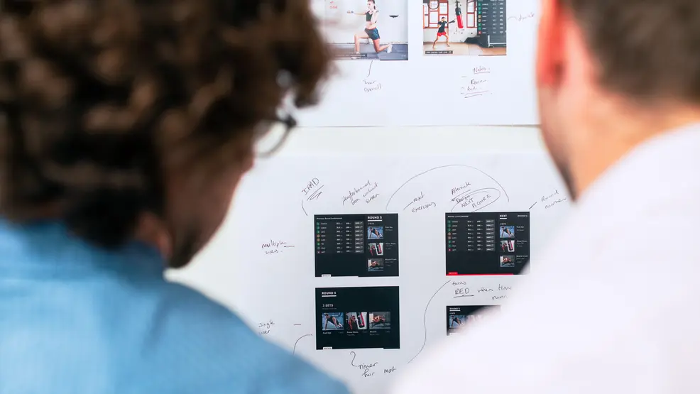Two people studying project plans on a wall