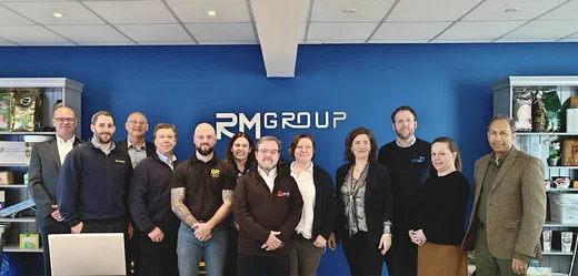 Group photo of attendees standing in front of the RM Group sign.