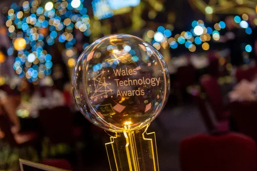 A glass Wales Technology Awards trophy on a table at an evening event.