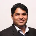 Gourav Tandon, India Country Head at Source Code Control, smiling in a dark suit over a navy jumper.