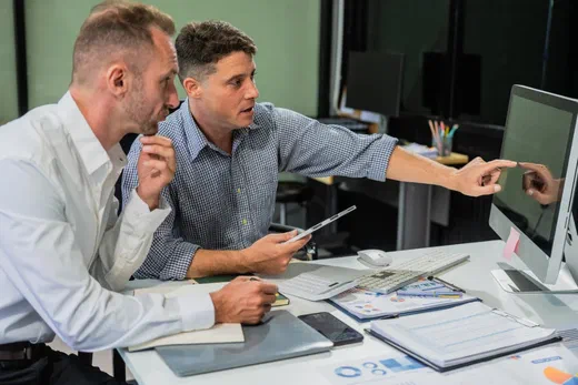 Finance team reviewing production cost data on a screen in a manufacturing facility