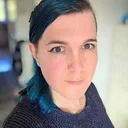 Close-up portrait of a woman with blue-dyed hair looking at the camera